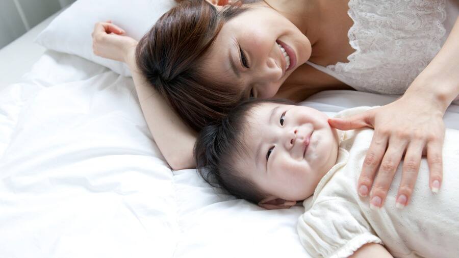 媽媽與寶寶躺在床上，對於寶寶長牙的事情感到興奮。	